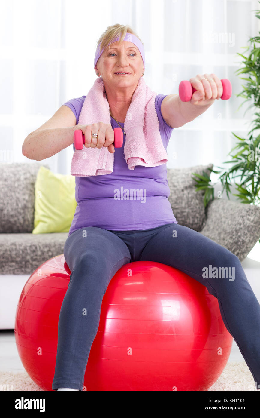 Senior mujer sentada sobre la pelota, y ejercicios de gimnasia Foto de stock