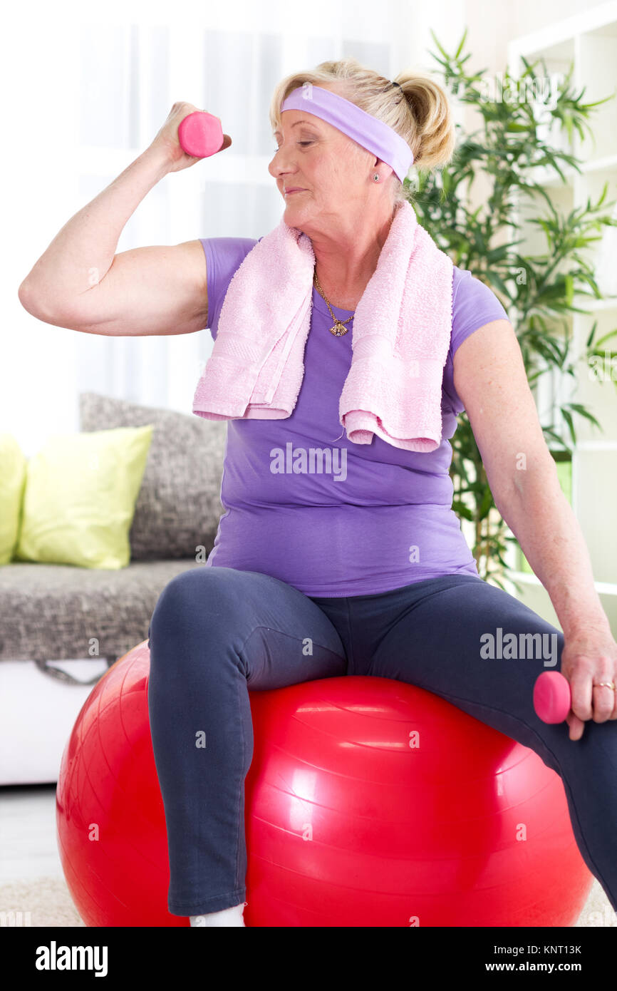 Senior mujer sentada sobre la pelota, y ejercicios de gimnasia Foto de stock