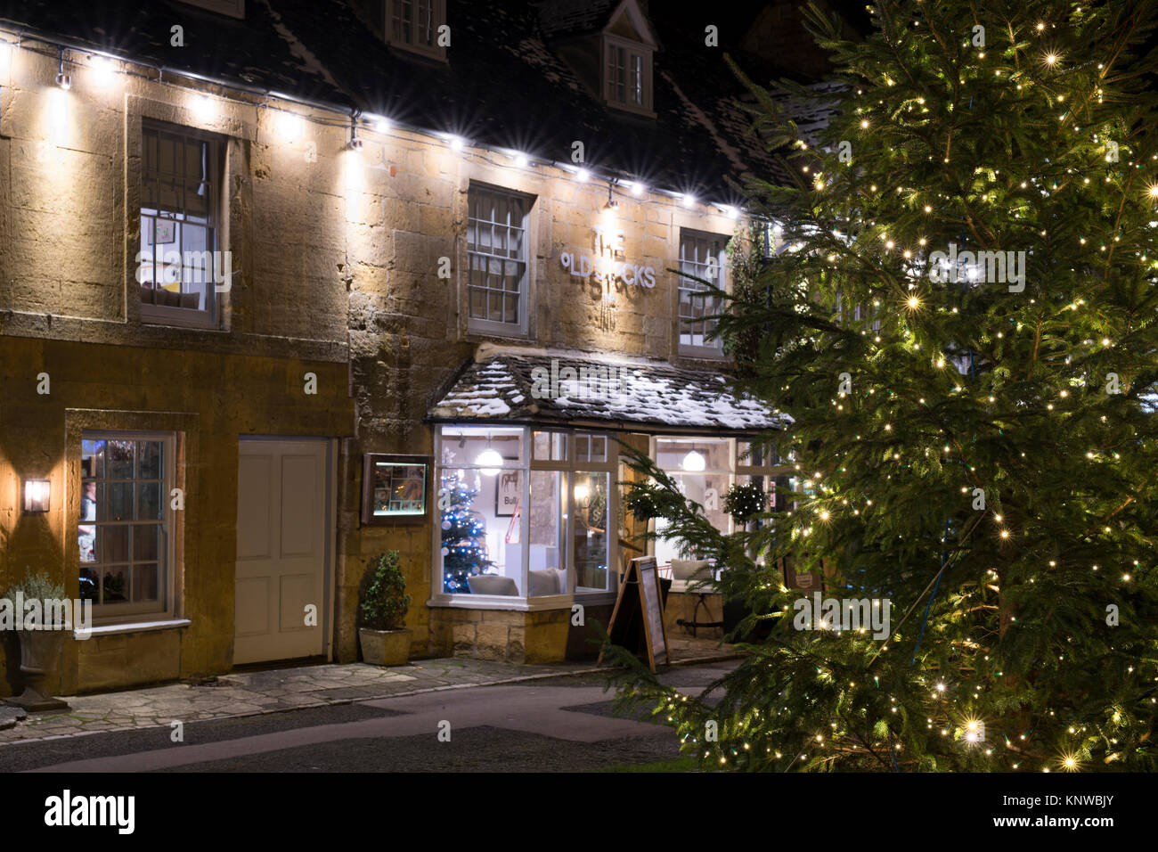 Árbol de Navidad y adornos en la noche delante de las antiguas existencias inn. Estibar en la Wold, Cotswolds, Gloucestershire, Inglaterra Foto de stock