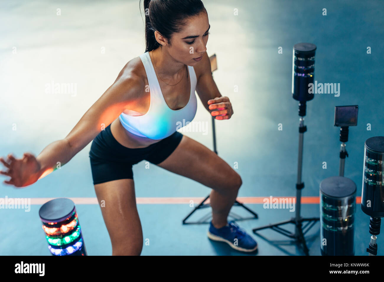 Ojo Mano mujer realizando entrenamiento de reacción con luces sensores en el laboratorio de ciencias deportivas. Atleta Femenina mejorar su equilibrio, las habilidades motoras y de visión por el lig Foto de stock