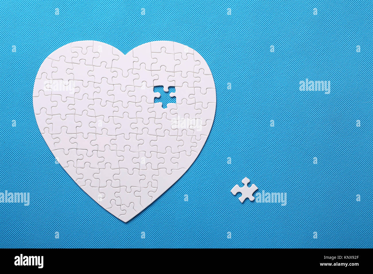 Detalles de un rompecabezas blanco sobre fondo azul. Un rompecabezas es un  puzzle de piezas pequeñas. Los detalles en forma de corazón. Manos folding  rompecabezas en blanco Fotografía de stock - Alamy