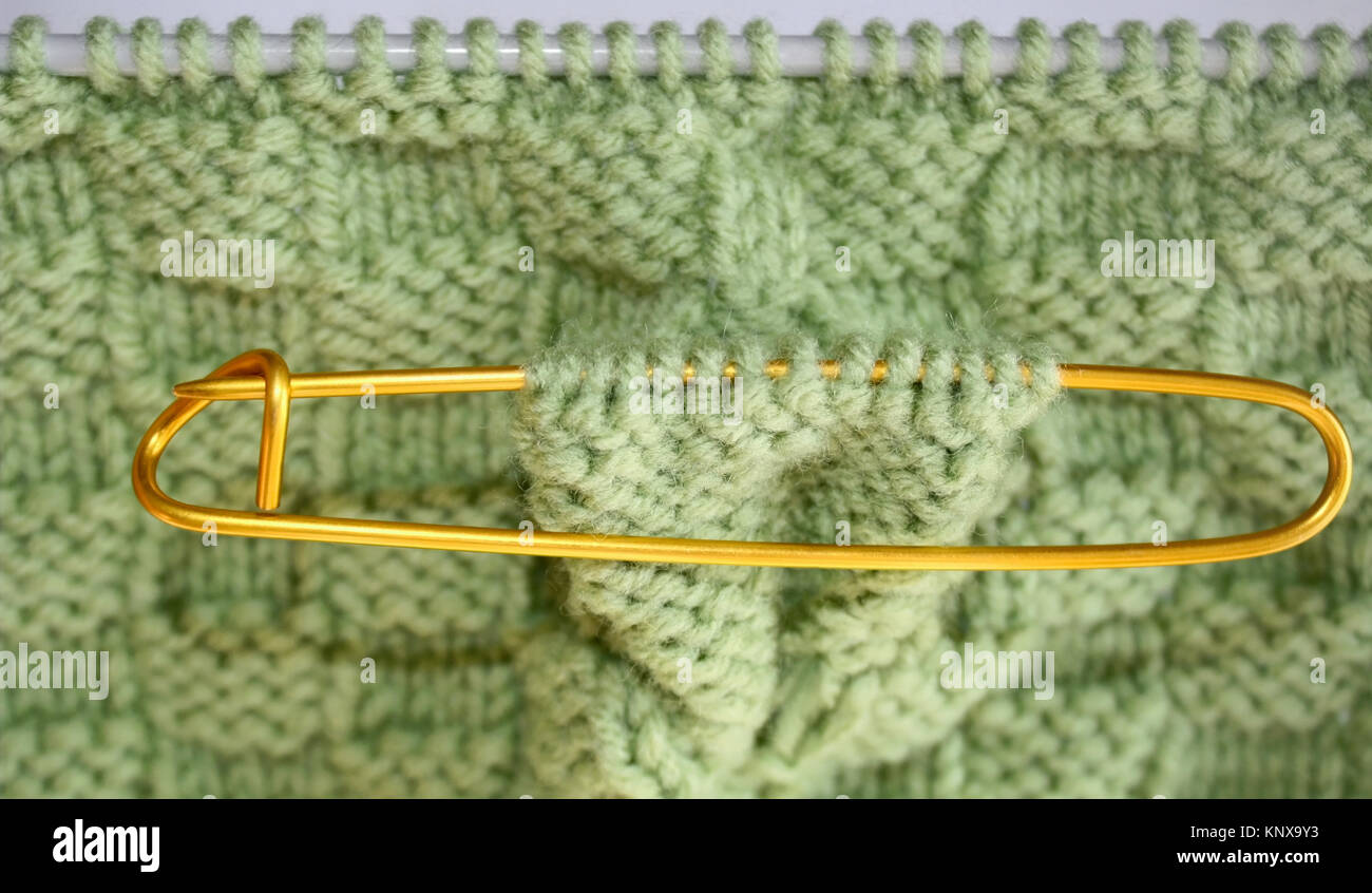 Cesta tejida de patrón de tejido en agujas de tejer en lana de color verde salvia. Titular de cosido en lugar marcar puntos extra para ser posteriormente tejida Foto de stock