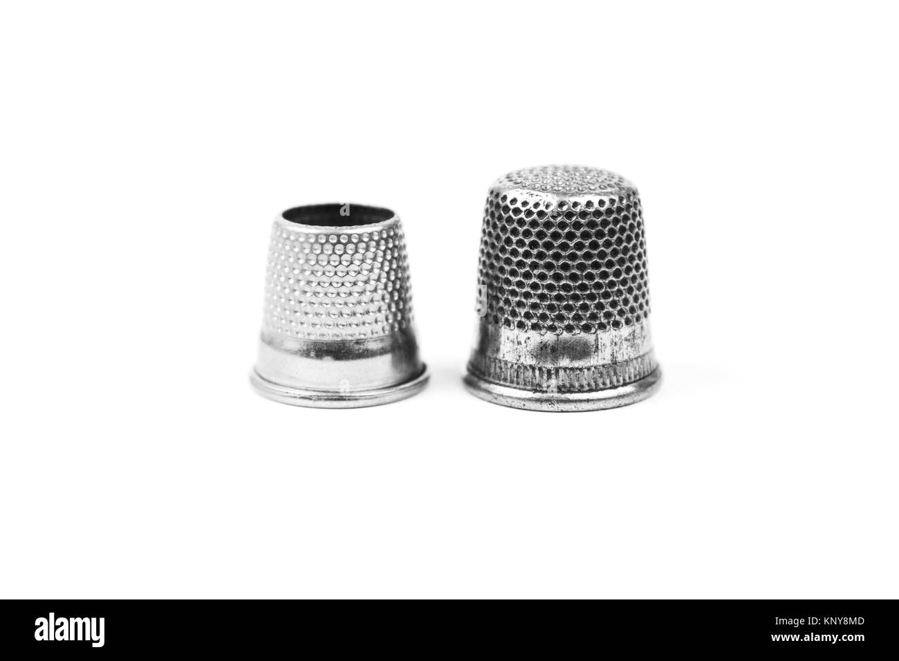 Dos metal plateado dedales de coser sobre un fondo blanco. Herramientas y accesorios de costura Foto de stock
