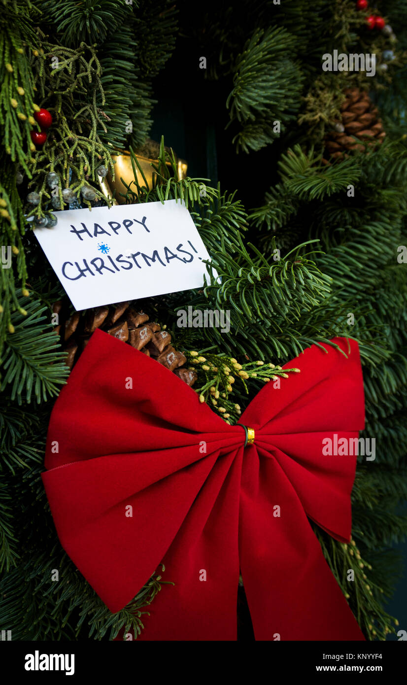 Navidad en puerta con arco rojo y el mensaje "Feliz Navidad" Foto de stock