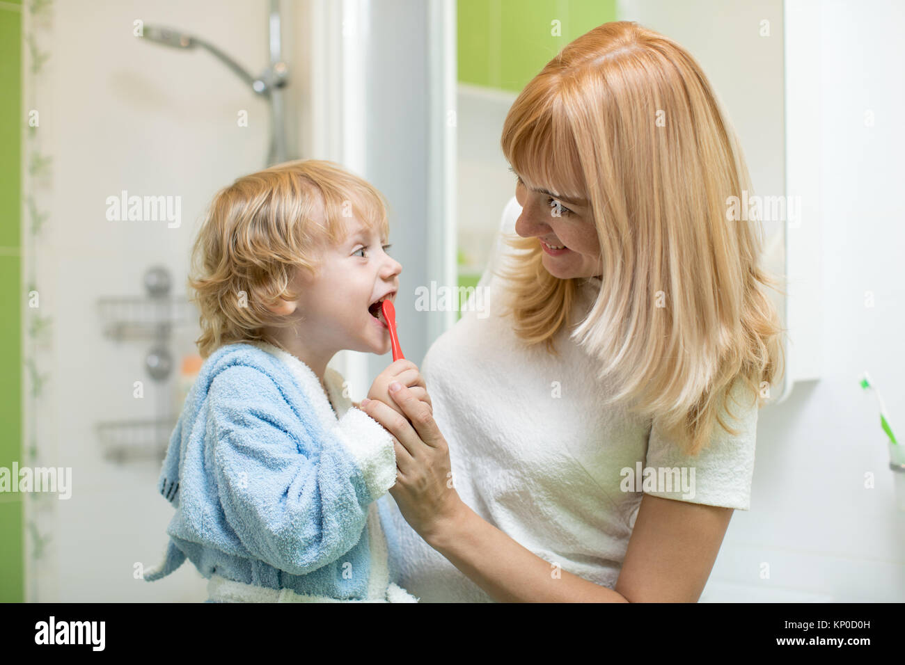 Madre de la enseñanza y ayudar a pequeño hijo cómo cepillar sus dientes Foto de stock