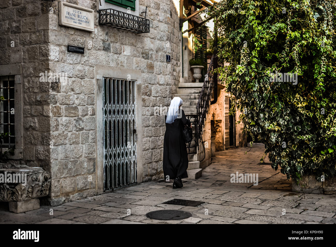 Una monja vistiendo un hábito pasea en la antigua ciudad de piedra de Split Croacia Foto de stock