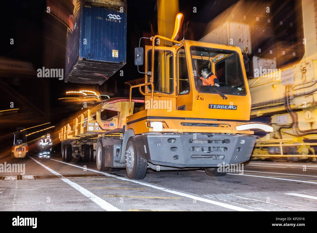 Camión de carga amarillo fijo está cargado con un contenedor azul de mercancías en Santa Cruz de Tenerife muelle en la noche Foto de stock