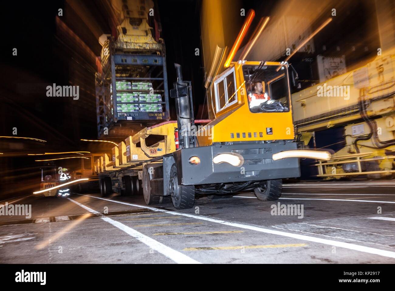 Camión de carga amarillo fijo está cargado con un contenedor azul de mercancías en Santa Cruz de Tenerife muelle en la noche Foto de stock