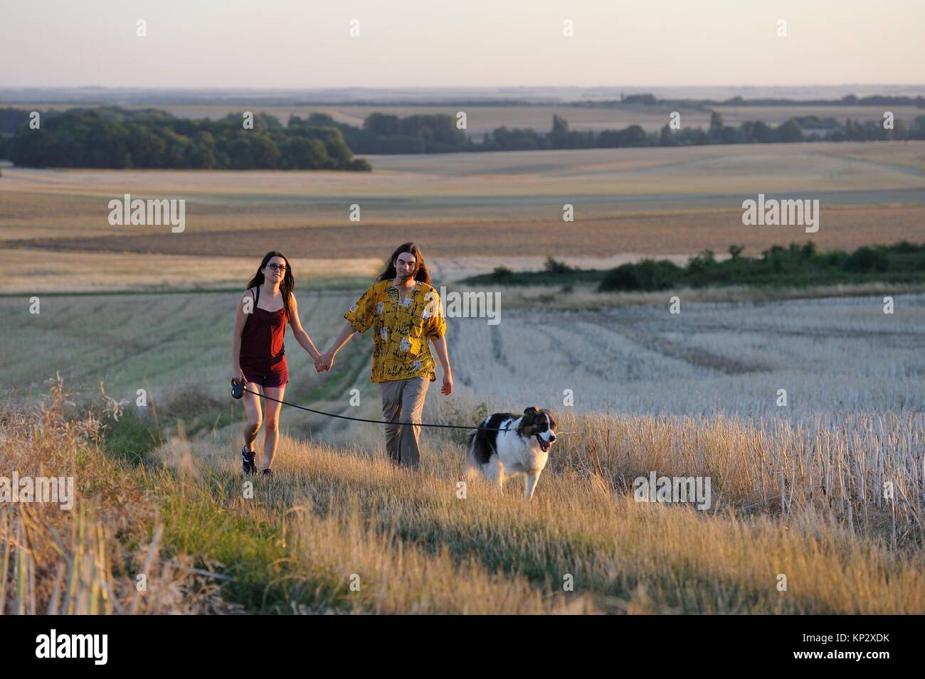 Par de jóvenes caminando con un perro alrededor Mittainville, departamento de Yvelines, la región Ile-de-France, Francia, Europa. Foto de stock