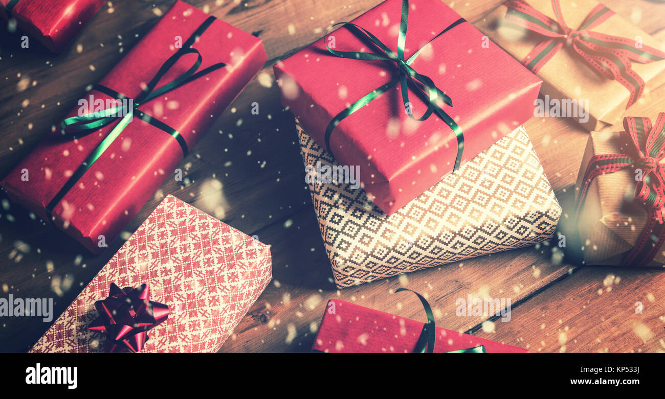 Regalos de Navidad envueltos sobre mesa de madera marrón y la nieve caída Foto de stock