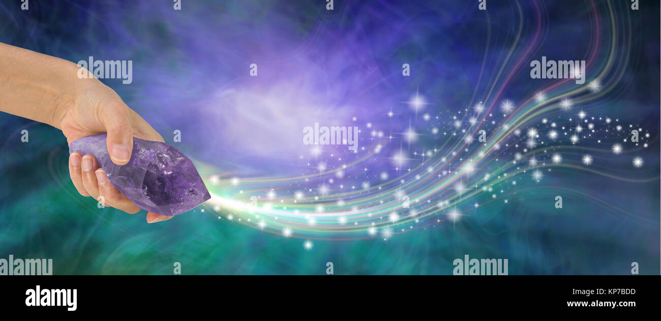 Mano femenina sosteniendo gran varita de Cuarzo amatista terminado expulsando brilla a través de un fondo de energía púrpura y jade con espacio de copia Foto de stock