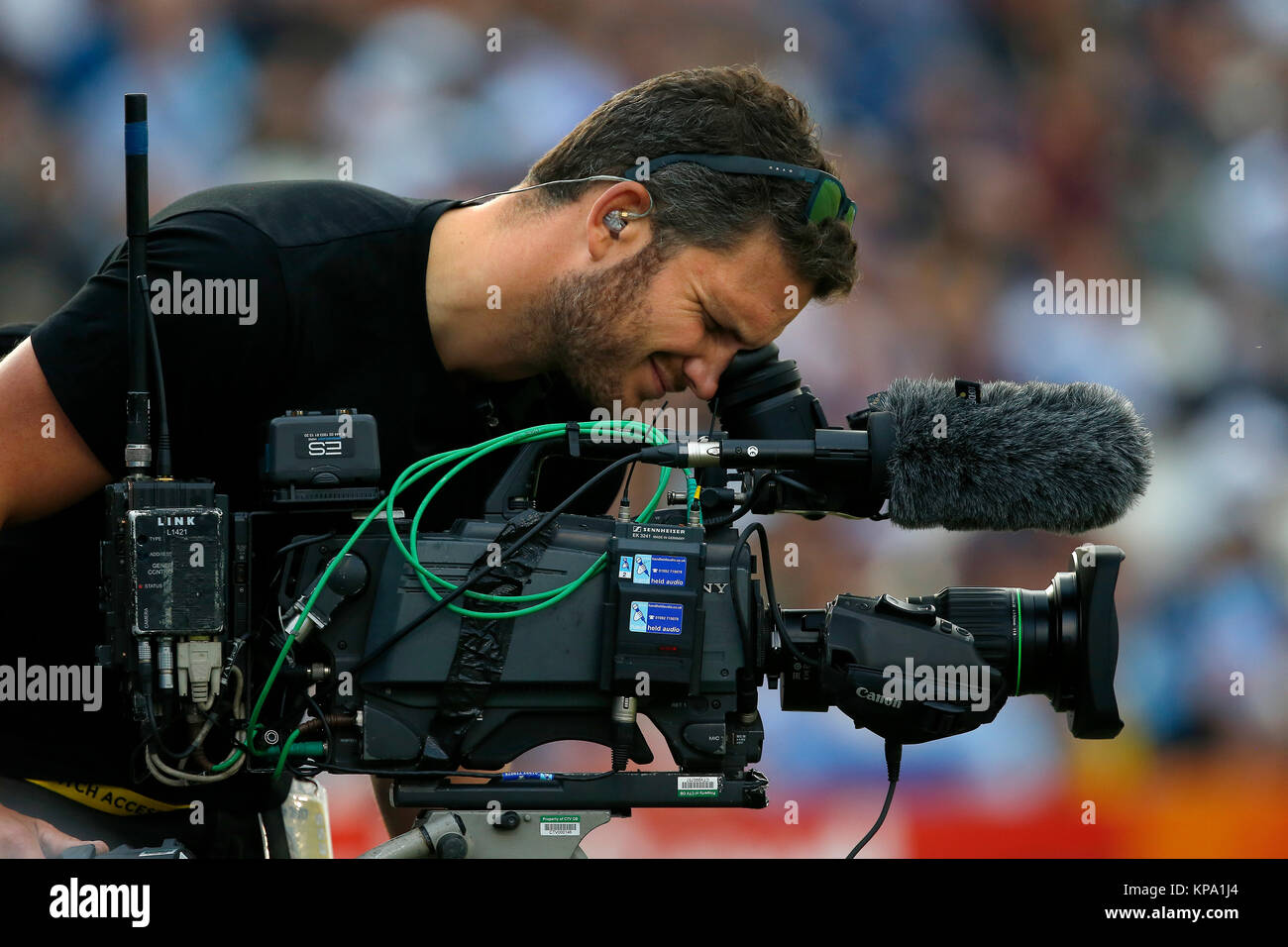 Un hombre de cámara de televisión filmando en un estadio deportivo. Foto de stock