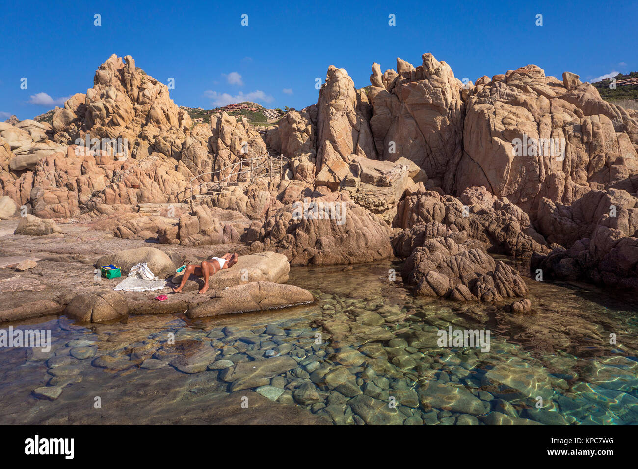 Mujer se toma un baño de sol en la idílica costa rocosa de Costa Paradiso, rocas de pórfido, Cerdeña, Italia, el mar Mediterráneo, Europa Foto de stock