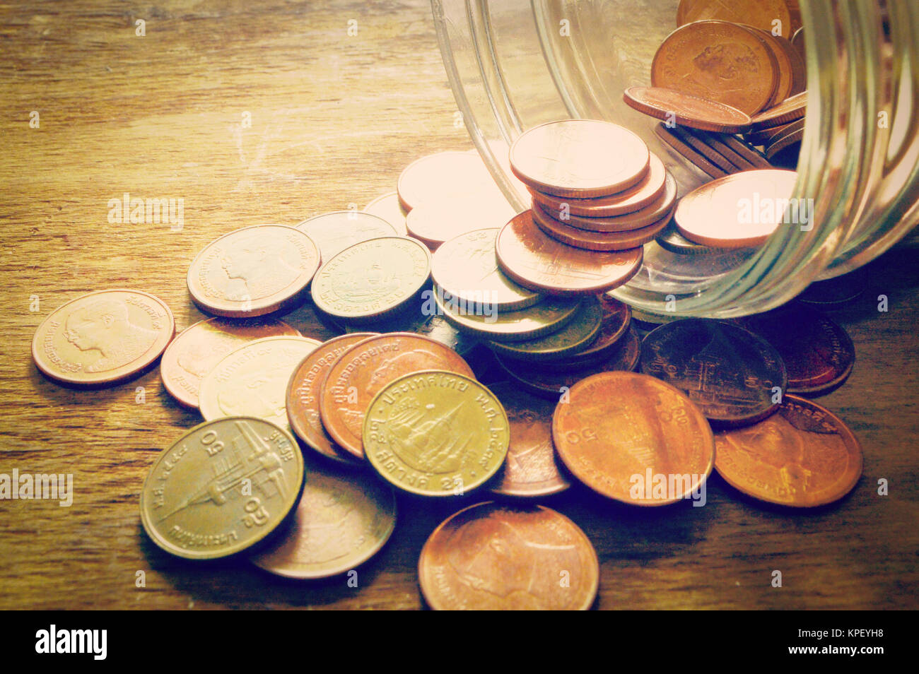 Monedas en botella sobre fondo antiguo de madera Foto de stock