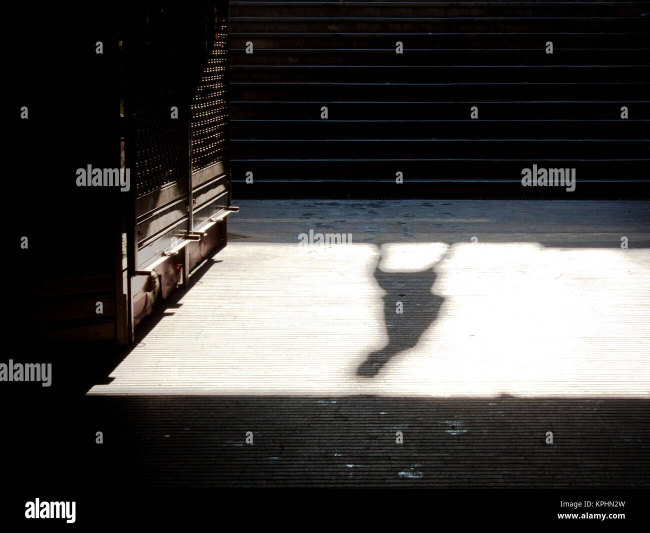 Ciudad soledad : sombra de una persona caminando solos y cerró la tienda de metro el domingo por la mañana en sepia blanco y negro Foto de stock