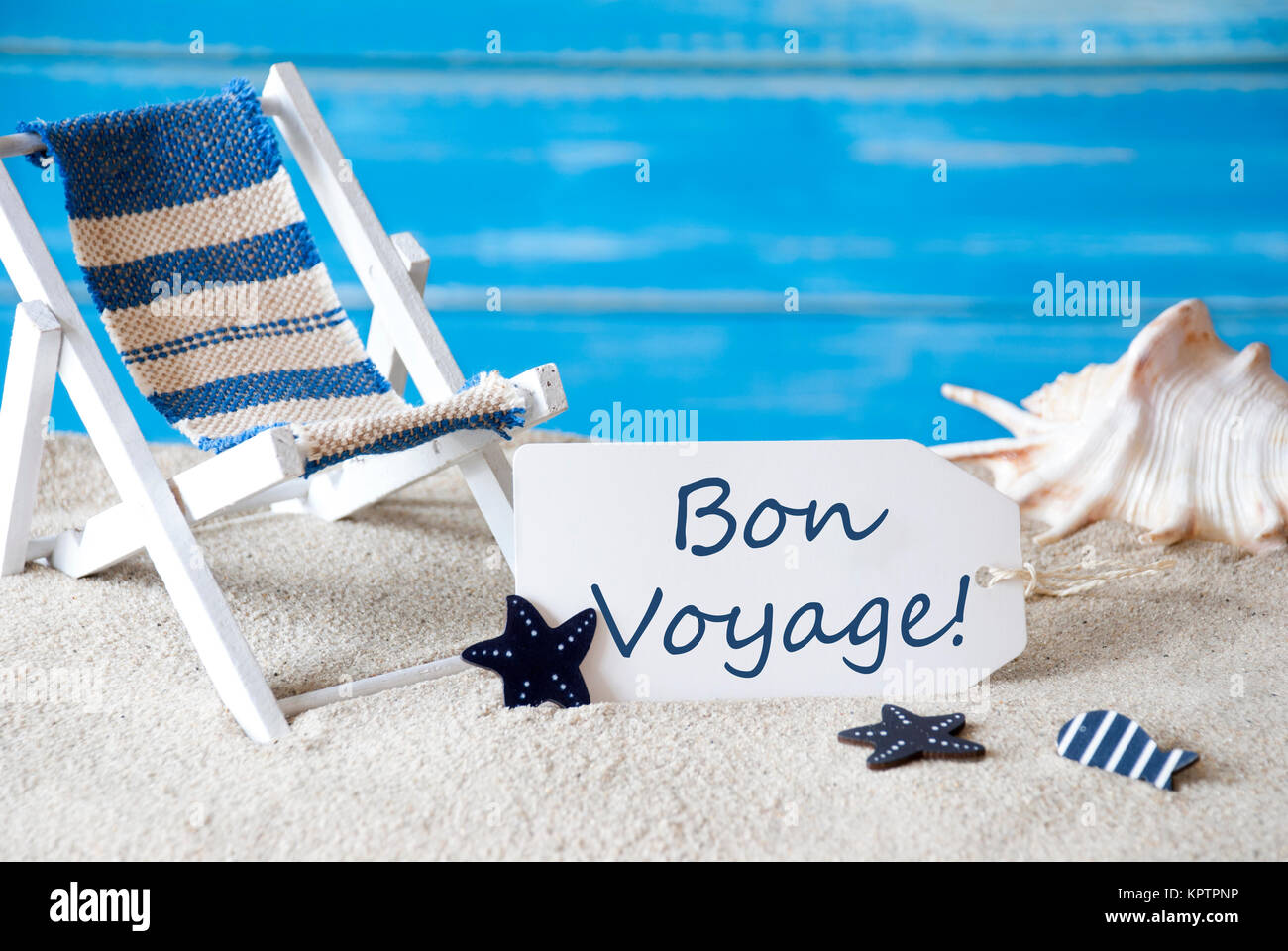 Etiqueta de verano con texto en francés Bon Voyage significa buen viaje.  Azul de fondo de madera. Tarjeta con saludos de vacaciones. Vacaciones de  playa, simbolizado por la arena, tumbona y Shell