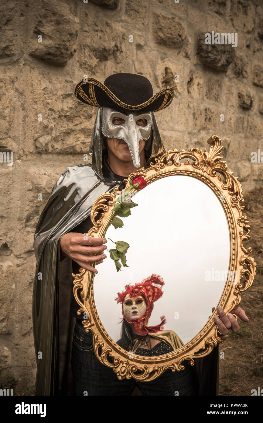 Hombre con máscara de pájaro veneciano, sosteniendo una rosa y un gran  espejo en su mano,carnaval Fotografía de stock - Alamy