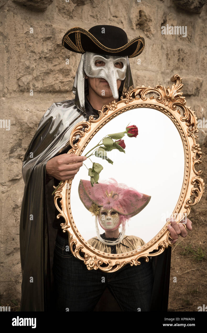 Hombre con máscara de pájaro veneciano, sosteniendo una rosa y un gran  espejo en su mano,carnaval Fotografía de stock - Alamy