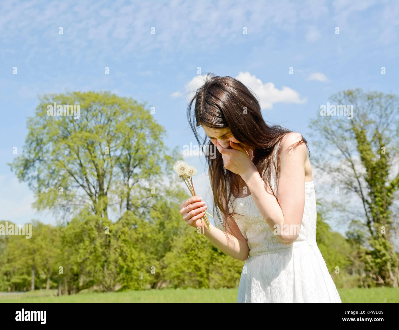 Mujer joven estornuda en un prado de flores Foto de stock