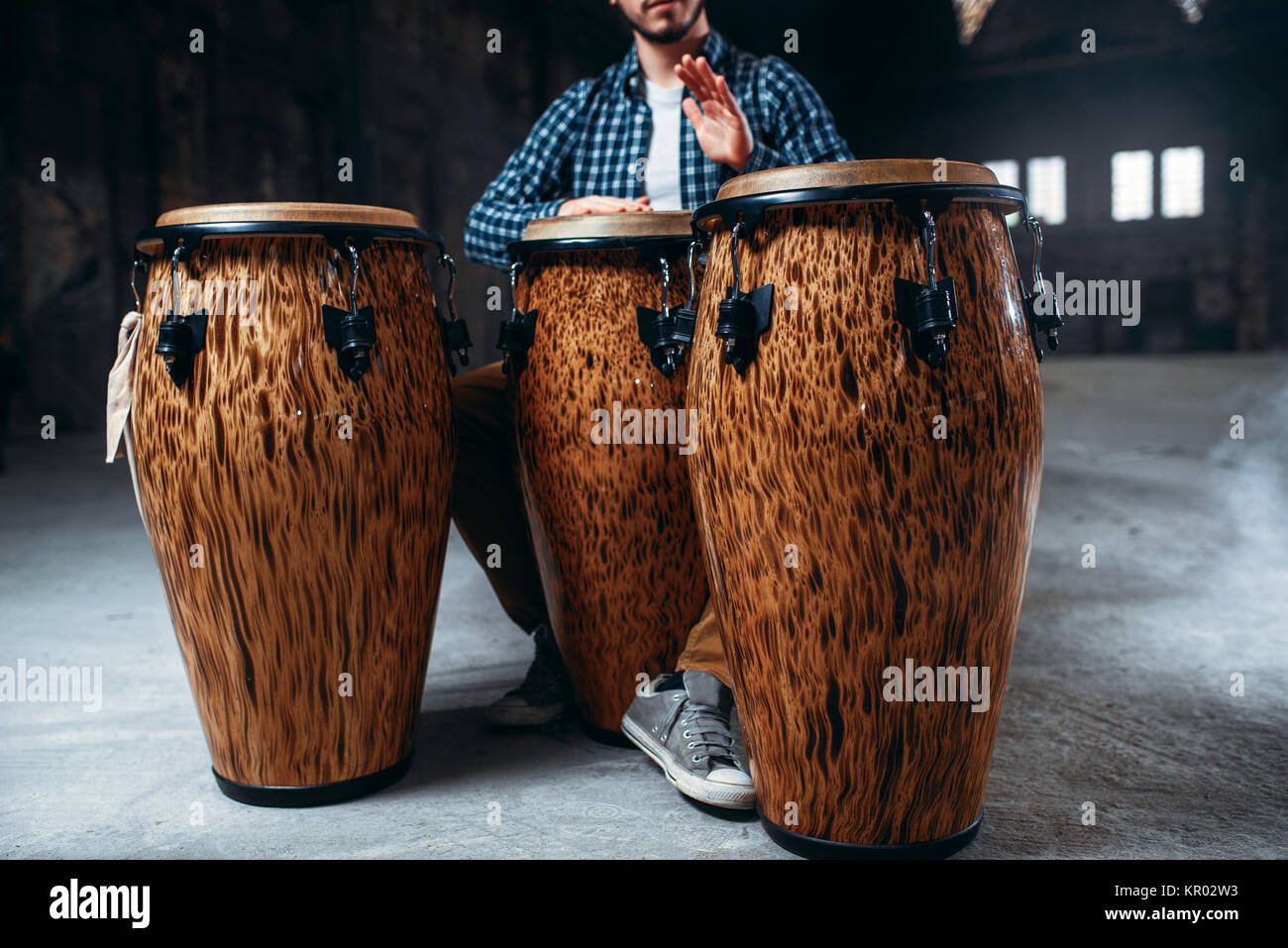 El baterista masculino juega en tambores de madera en la tienda de fábrica,  músico en movimiento. Bongo, instrumento de percusión musical, la música  étnica Fotografía de stock - Alamy