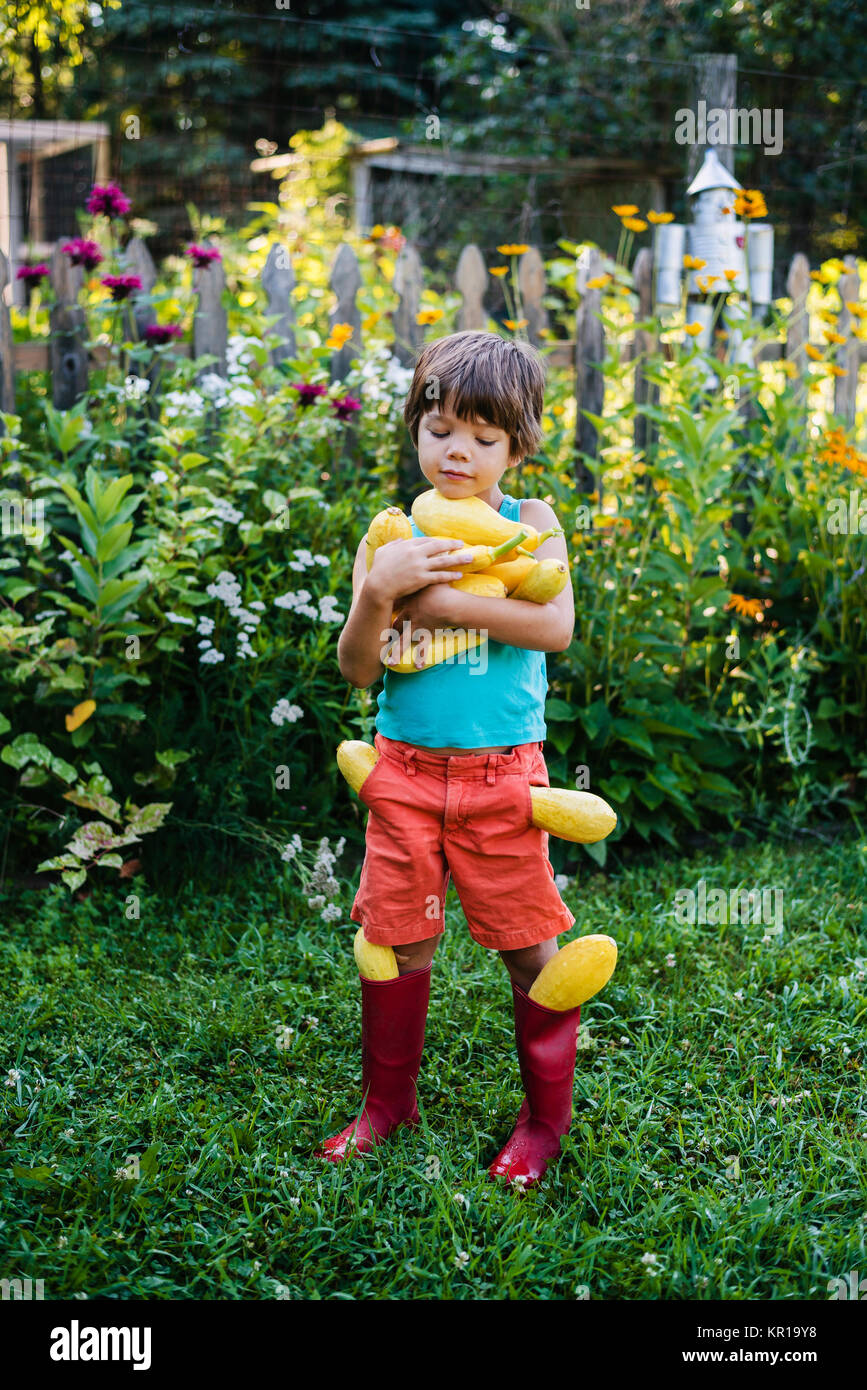 Chico llevando la cosecha fresca de verano de squash Foto de stock
