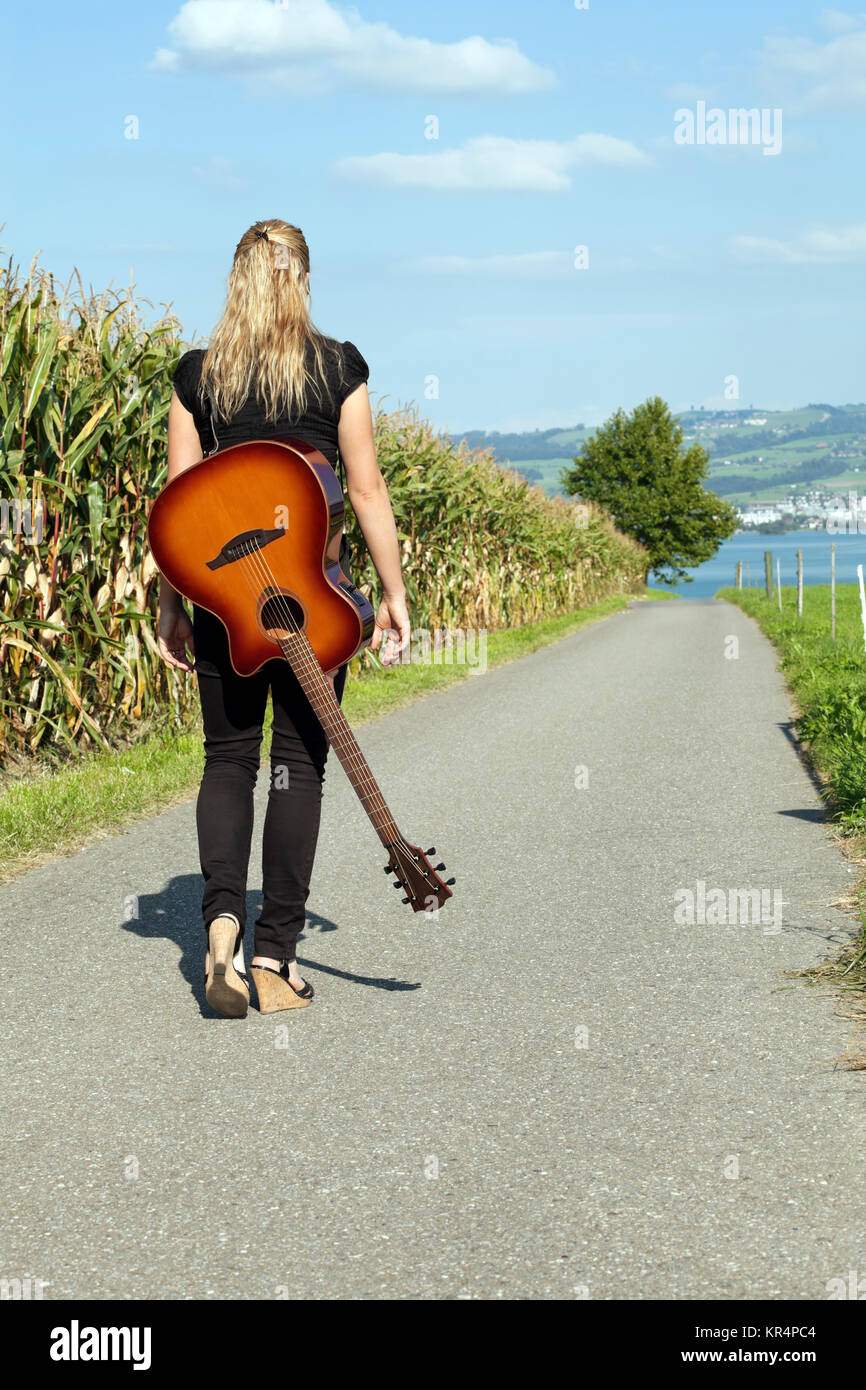 Foto de un guitarrista femenina caminando por una carretera con su guitarra  colgada sobre su espalda Fotografía de stock - Alamy