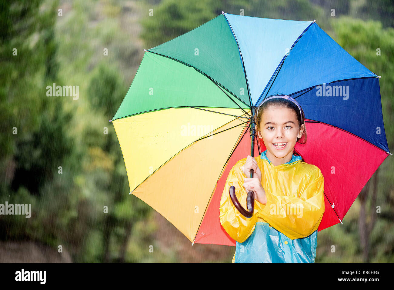 Niña feliz con coloridos paraguas y chubasquero jugando bajo la lluvia  Fotografía de stock - Alamy