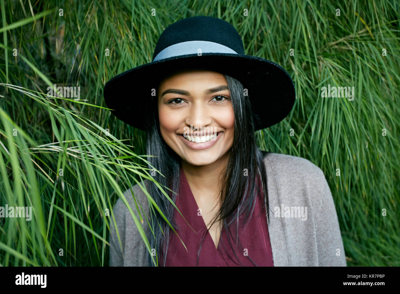 Retrato de mujer de raza mixta sonriente cerca de follaje Foto de stock