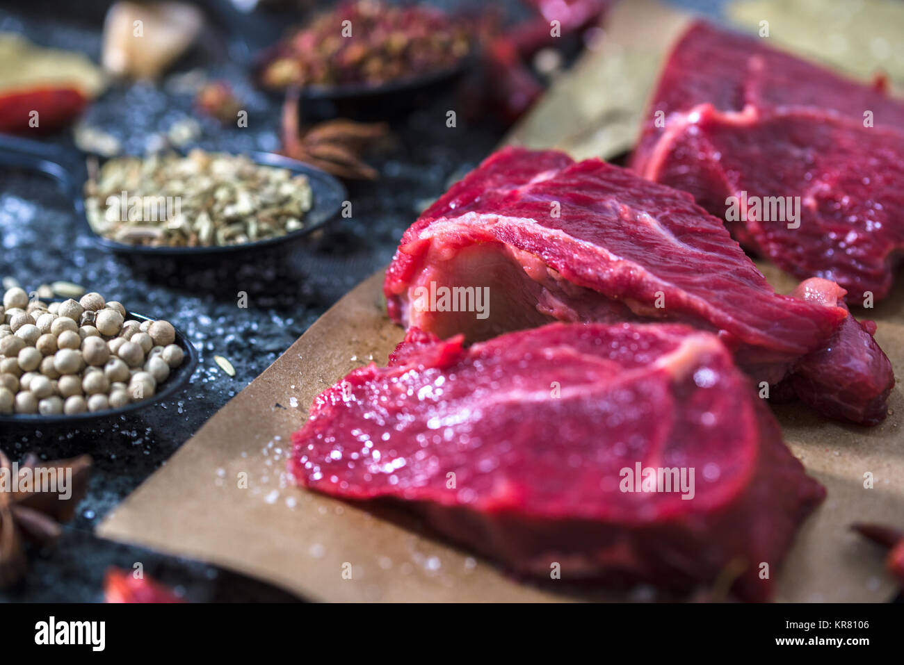 La carne cruda. Filete de carne cruda sobre una tabla para cortar con romero y especias. Foto de stock