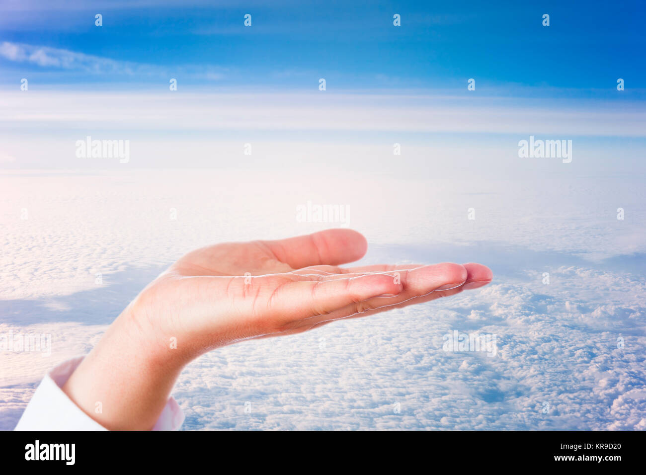 Abrir la palma de la mano por encima de las nubes Foto de stock