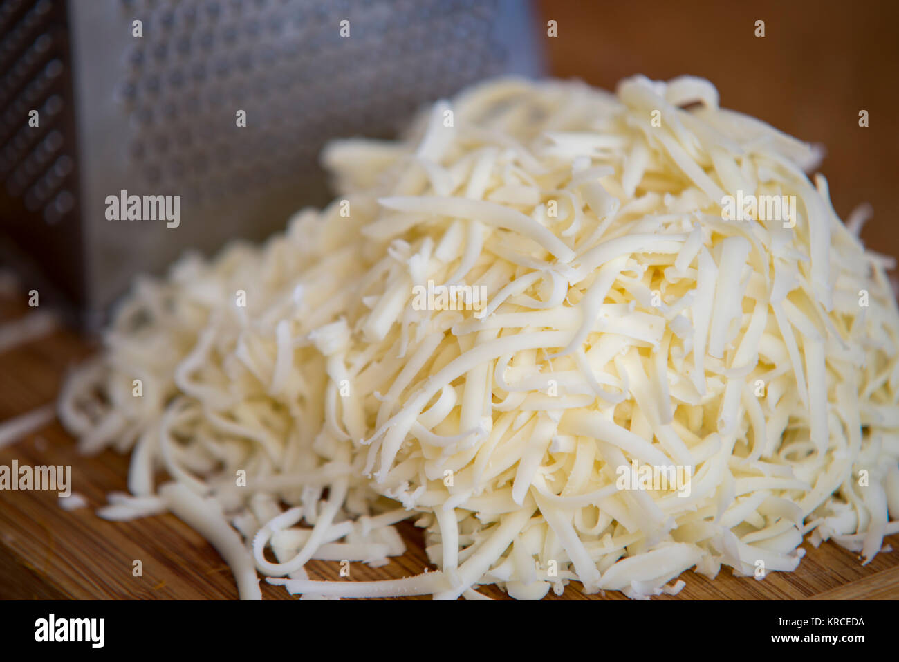 Queso mozzarella desmenuzado sobre una tabla para cortar con un rallador  Fotografía de stock - Alamy