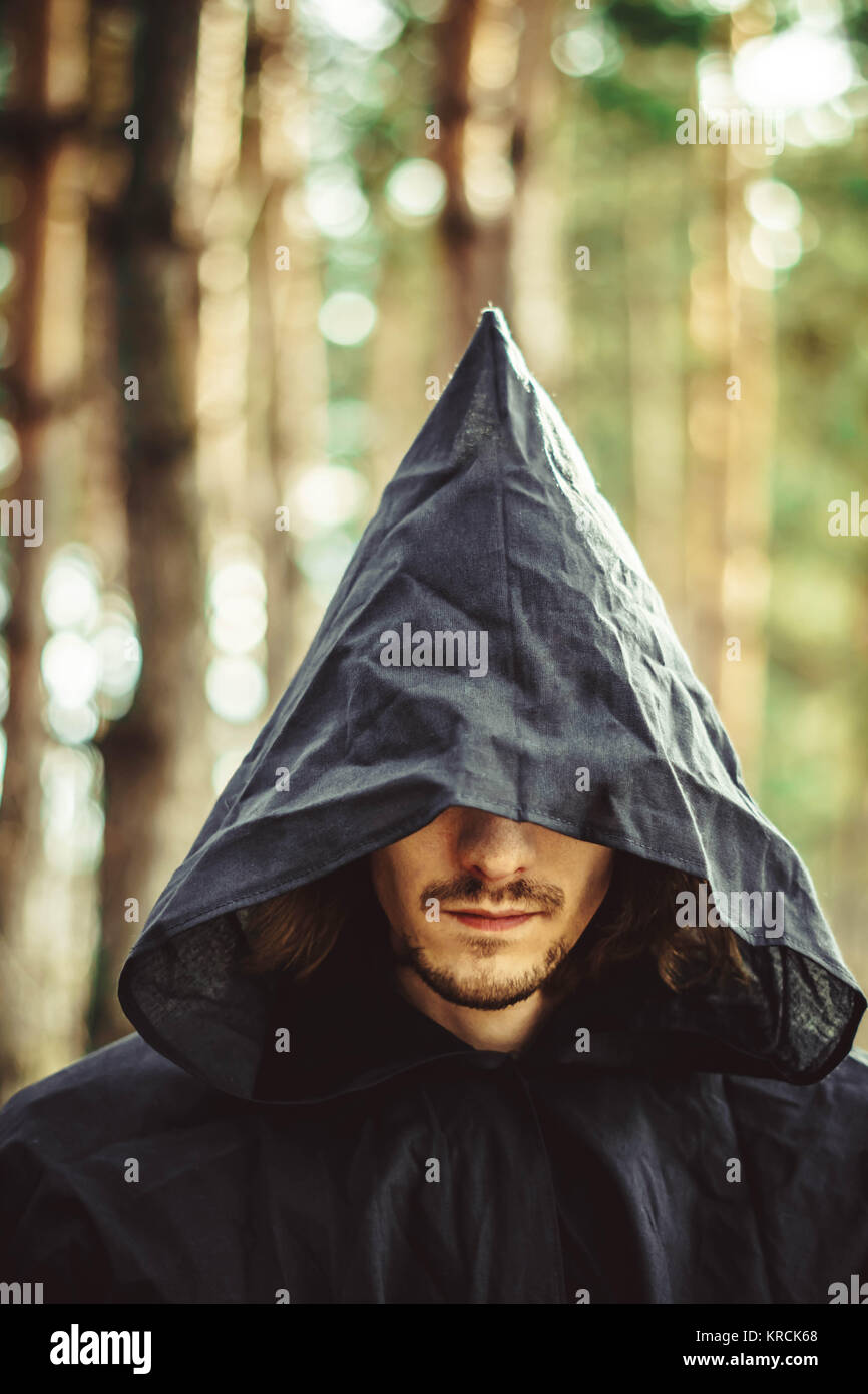 Sucio silencio golpear Un hombre tenebroso en una capucha negra en el bosque Fotografía de stock -  Alamy