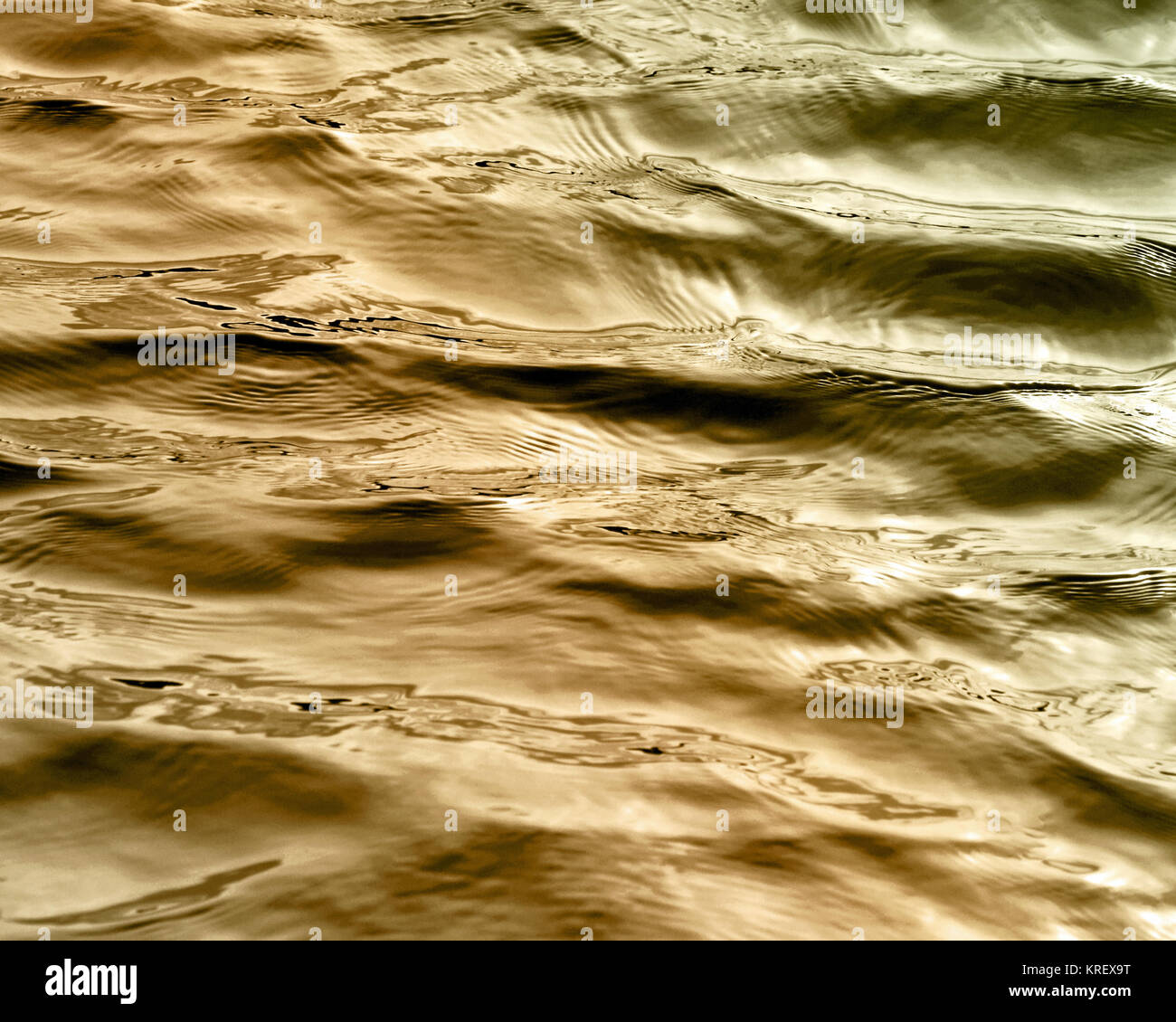 Hermosas aguas con suaves ondas en la superficie en tonos de oro Foto de stock