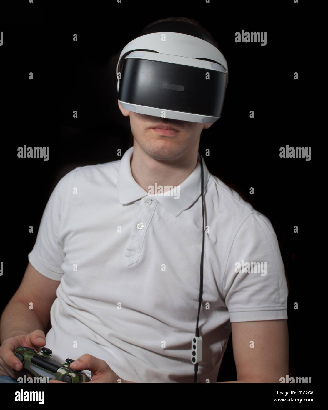Sentado joven juega en el juego de ordenador con casco de RV Foto de stock