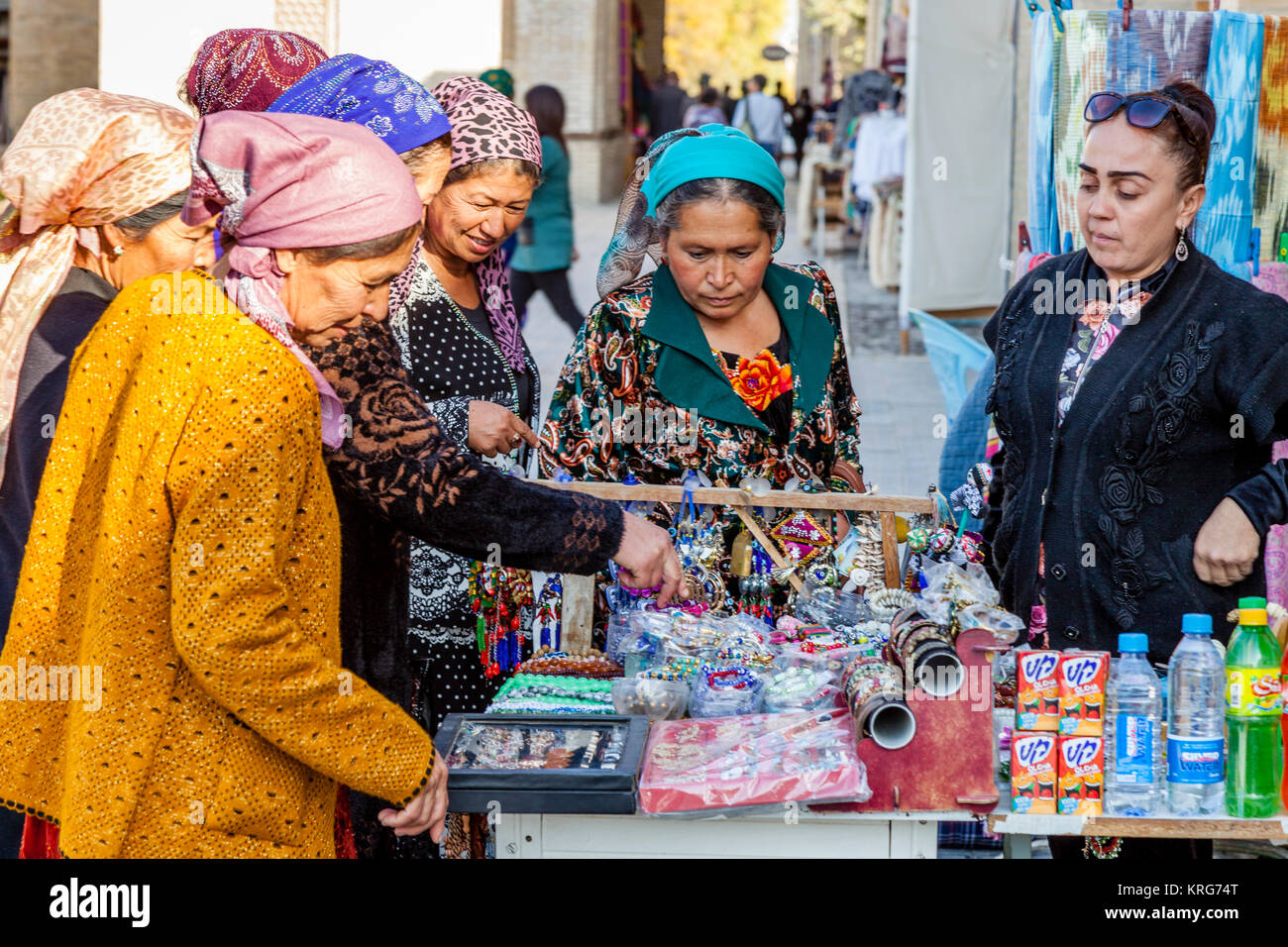 Un grupo de mujeres uzbekas Comprar artículos desde un puesto en el mercado, Bukhara, Uzbekistán Foto de stock
