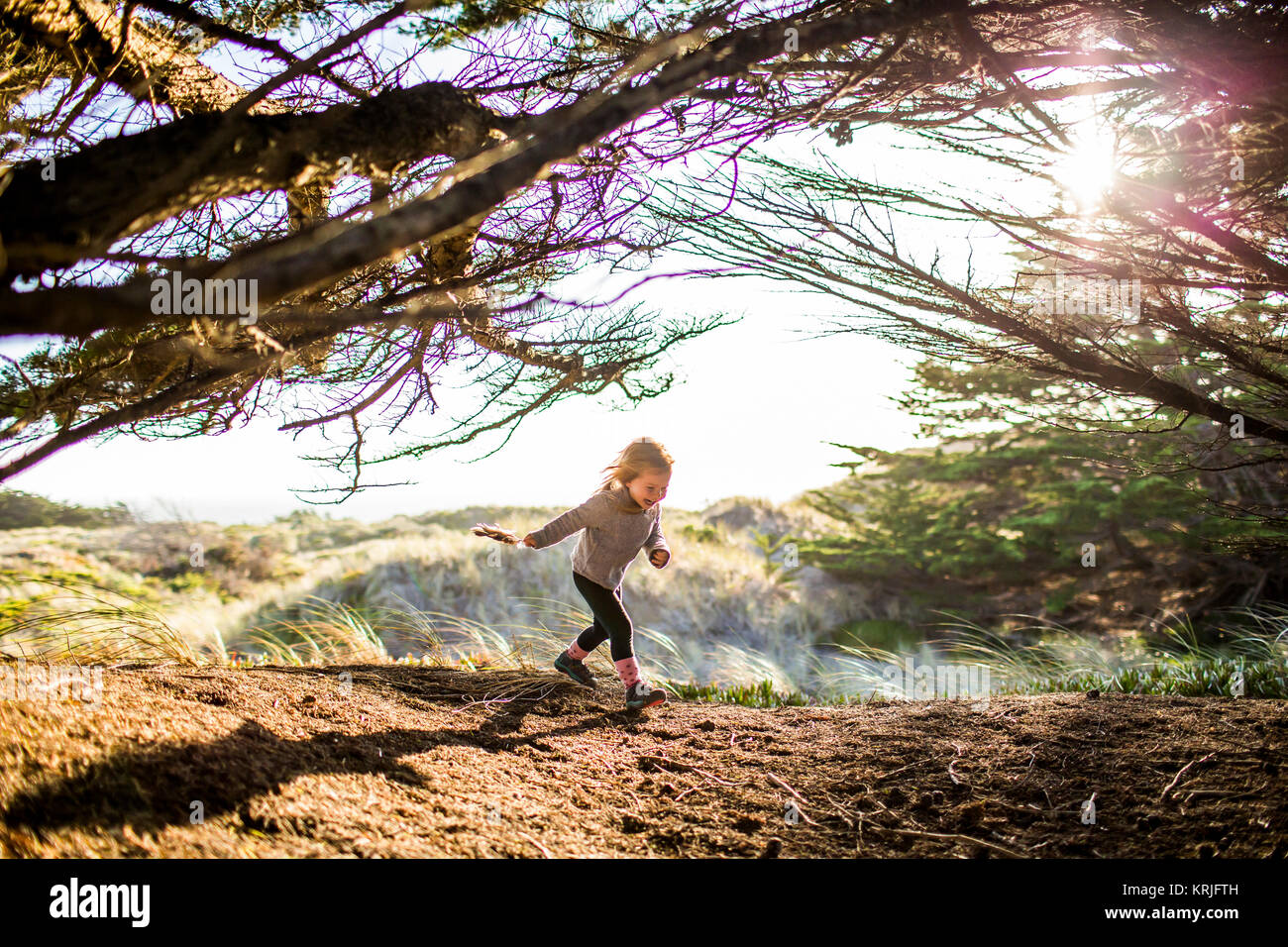 Caucasian chica corriendo bajo las ramas de un árbol Foto de stock