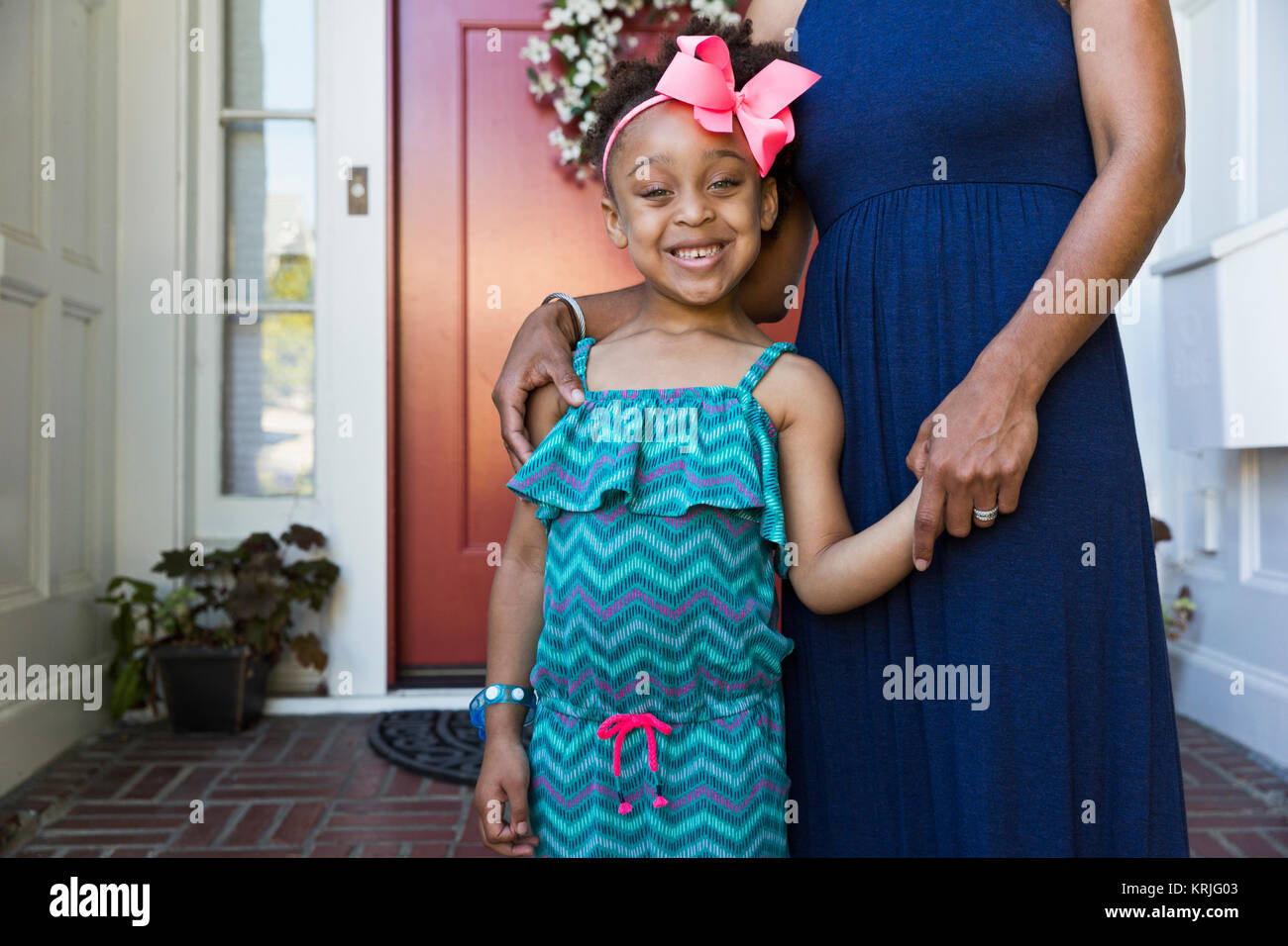 Sonriente, madre e hija de raza mixta de pie en la parte delantera stoop Foto de stock