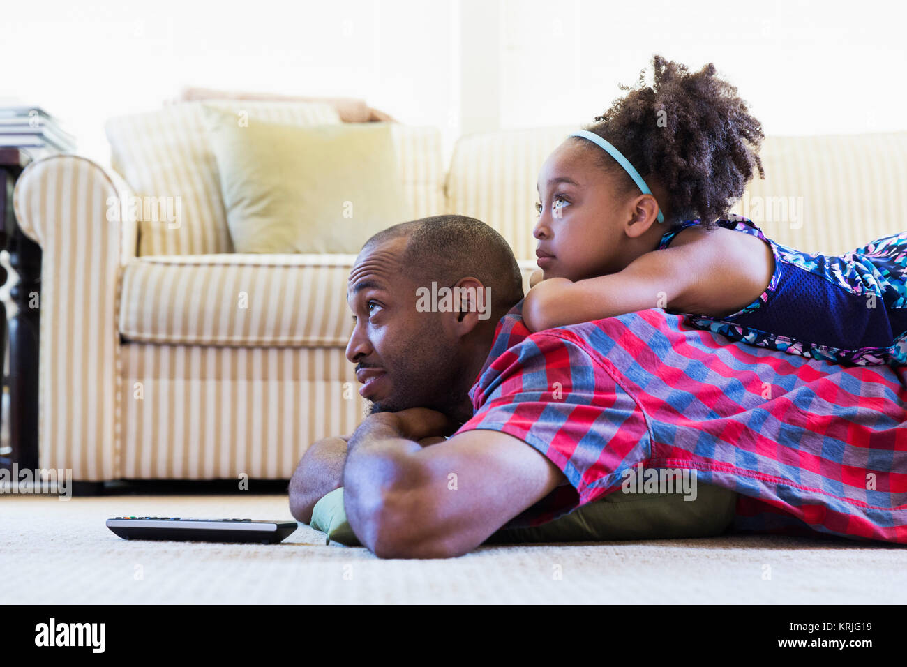 El padre y la hija de raza mixta tendido en el suelo mirando televisión Foto de stock