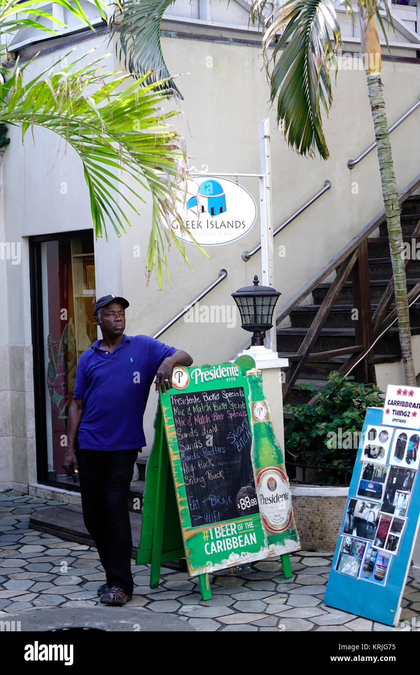 Las Islas Griegas, Restaurante y Bar en Nassau, Las Bahamas ofrece mariscos frescos, carne de cerdo y platos de pollo con cerveza de Bahamas. En Bahamas un hombre parado Foto de stock