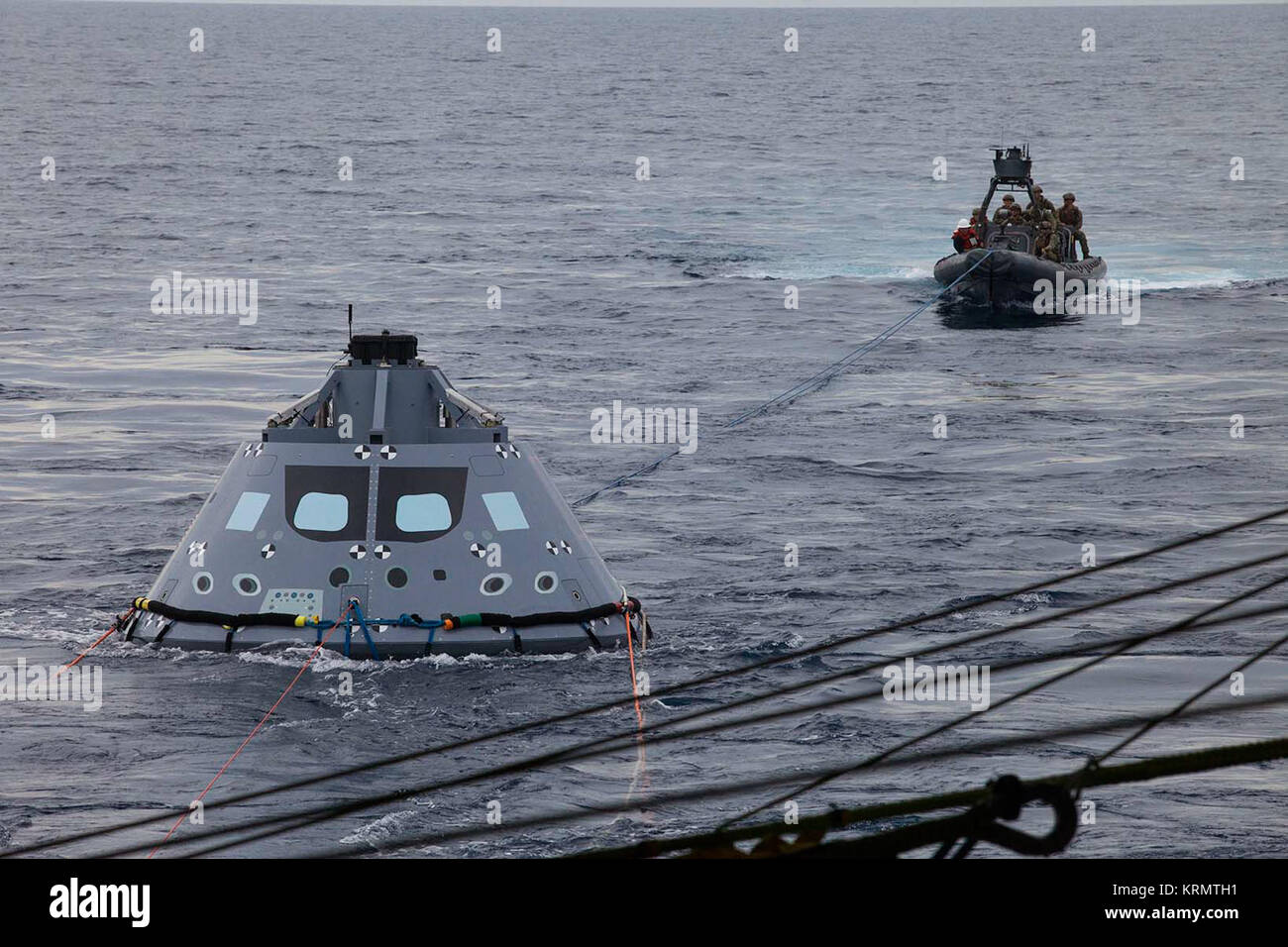 Los buzos de la Marina de EE.UU. y otros miembros del personal en un casco rígido Zodiac adjunta líneas de atado para una versión de prueba de la tripulación Orion durante la prueba de recuperación en marcha el módulo 5 en el océano Pacífico frente a la costa de California. Tierra de la NASA y de desarrollo de sistemas y programas de operaciones de la Marina de los EE.UU. están llevando a cabo una serie de pruebas con el USS San Diego, varias embarcaciones y equipos para practicar para la recuperación de Orión en su regreso de misiones en el espacio interestelar. Las pruebas permitirá al equipo para demostrar y evaluar los procesos de recuperación, procedimientos, hardware y personal en aguas abiertas. Orion es el Foto de stock