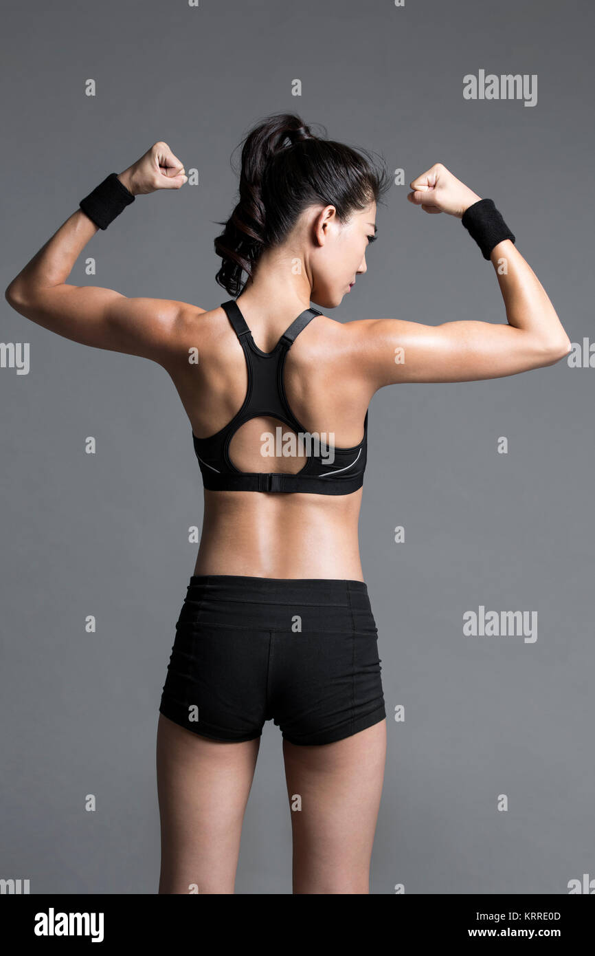 Vista trasera del joven atleta femenina flexionando los músculos Foto de stock