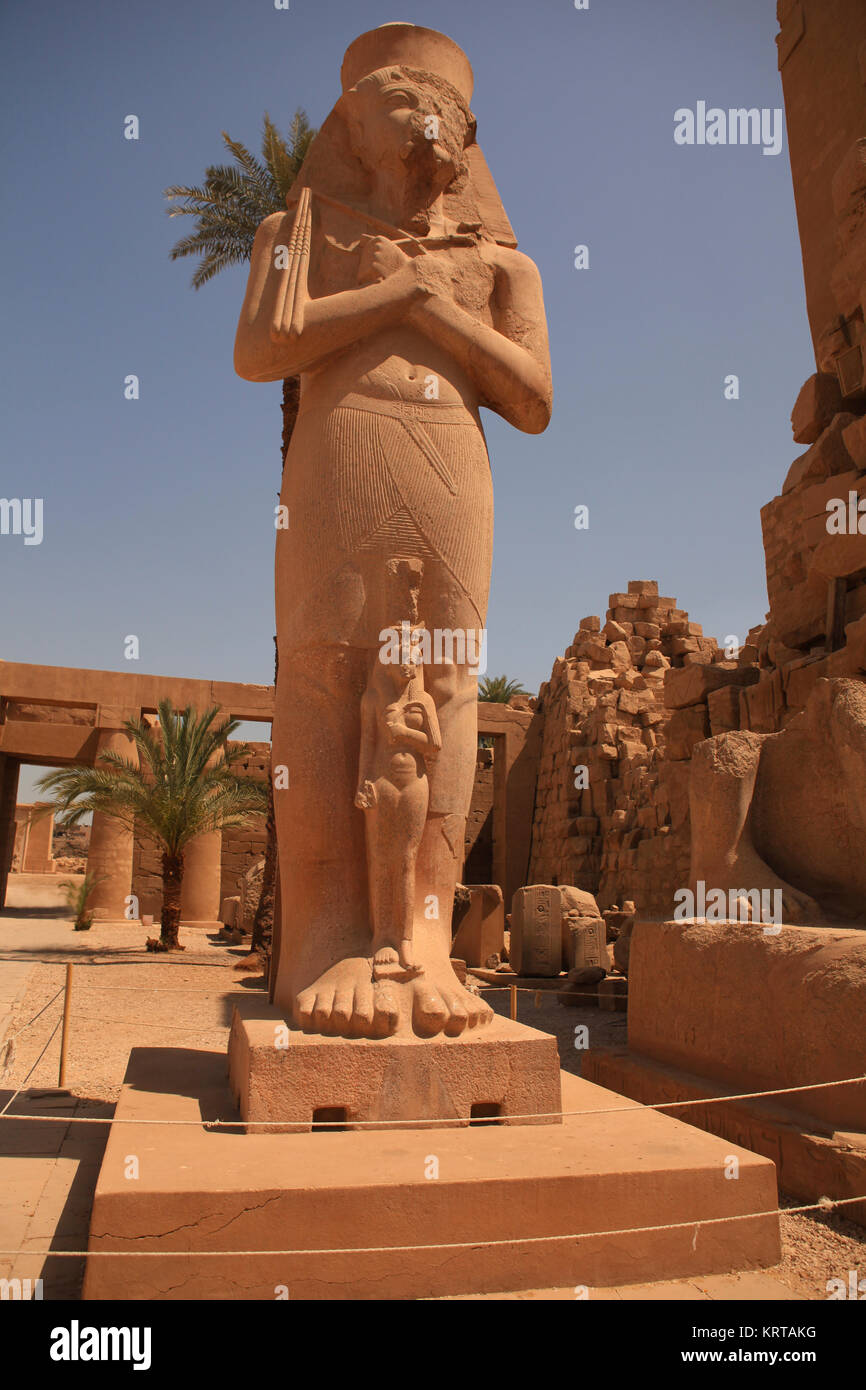 La estatua de Ramsés II con los brazos cruzados, sosteniendo crook (mayal y símbolos de la monarquía), con la pequeña estatua de la Princesa doblada anta en su encaje, Gr Foto de stock