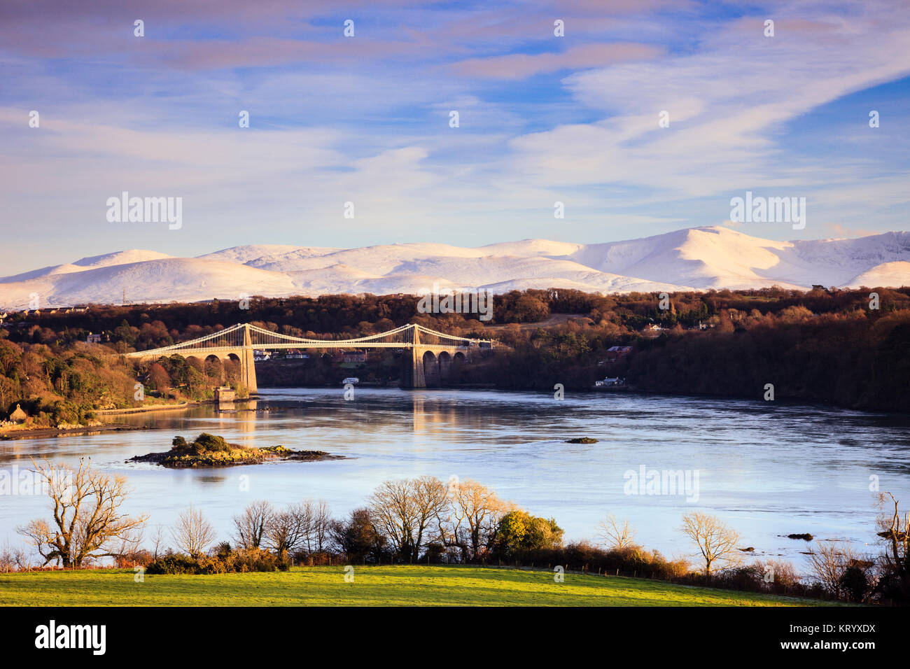 Vista panorámica del estrecho de Menai con Thomas Telford del puente colgante de Menai y en invierno la nieve en las montañas Snowdonia. Puente de Menai Anglesey al norte de Gales, Reino Unido Foto de stock