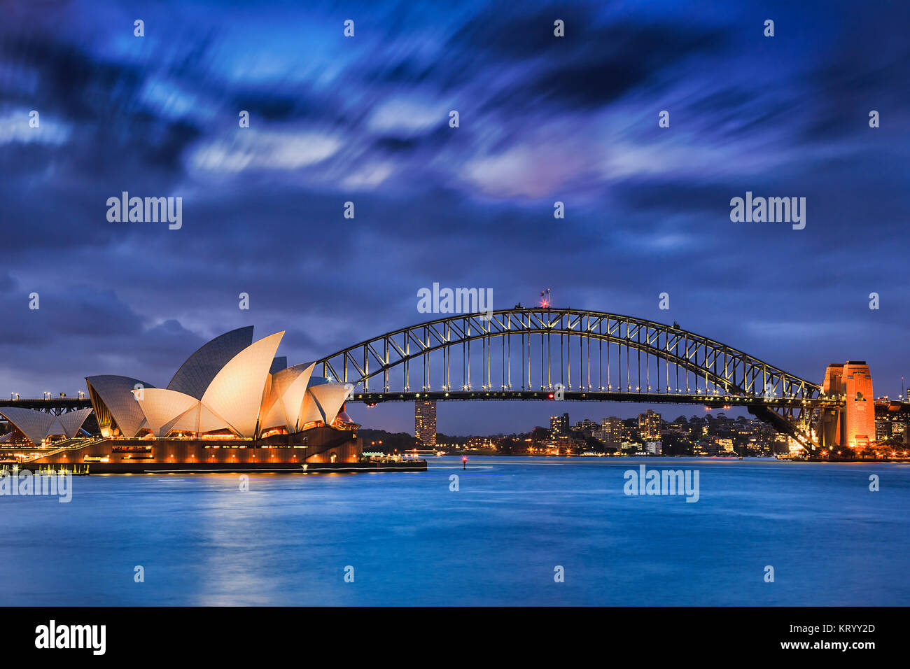 Sydney, Australia, el 18 de marzo de 2017: la mundialmente famosa Sydney Opera House y el puente Harbour al atardecer. Nubes borrosa y las luces de monumentos reflejan en blur Foto de stock