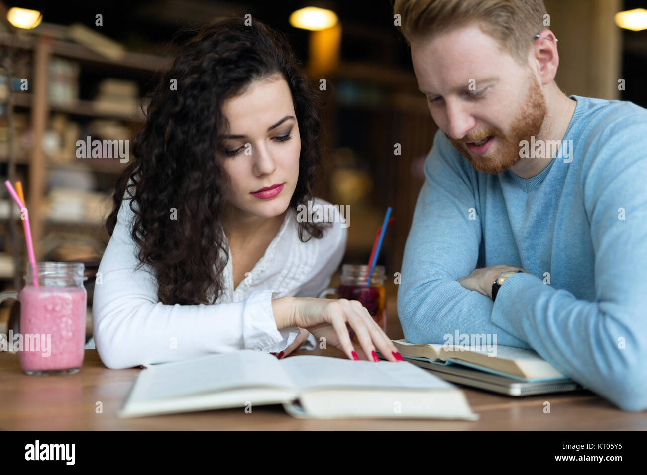 Los jóvenes estudiantes dedicar tiempo a la lectura de libros en la cafetería. Foto de stock