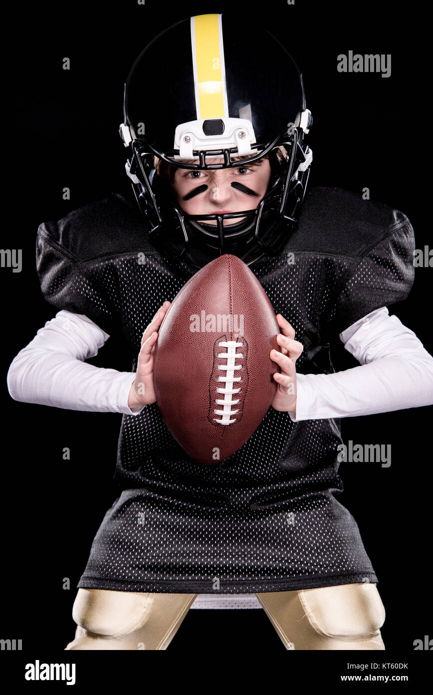 Niñito agresiva en la protección sportswear jugando fútbol americano con  bola Fotografía de stock - Alamy