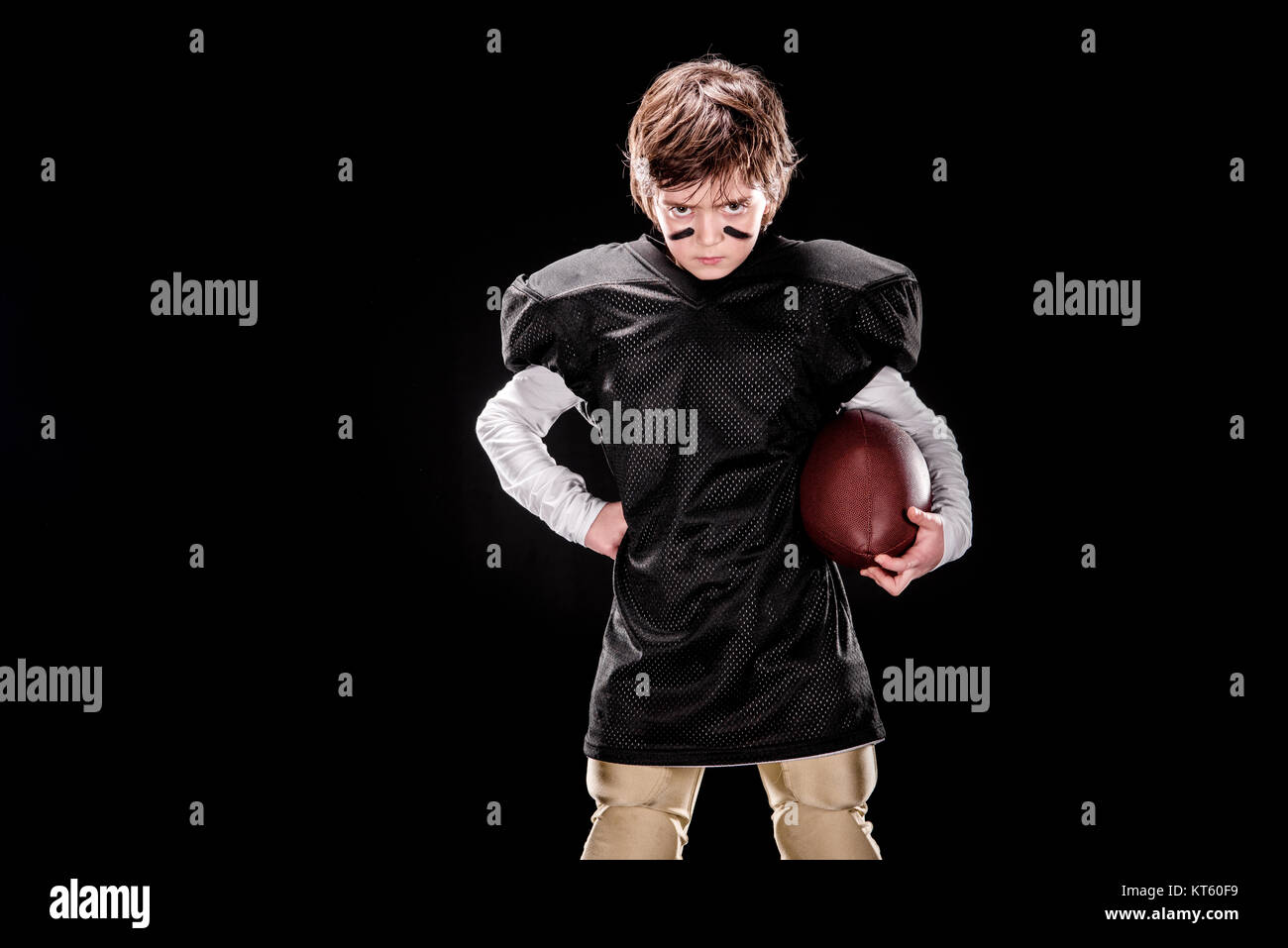 Jugador de fútbol americano chico enojado sosteniendo la bola y mirando a la cámara Foto de stock