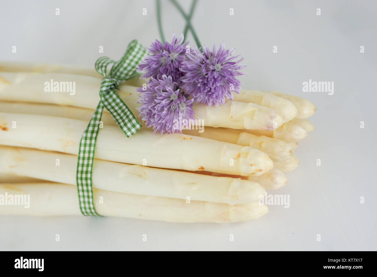 espárragos bellamente decorados con cebollino, flores y cinta con batatas Foto de stock