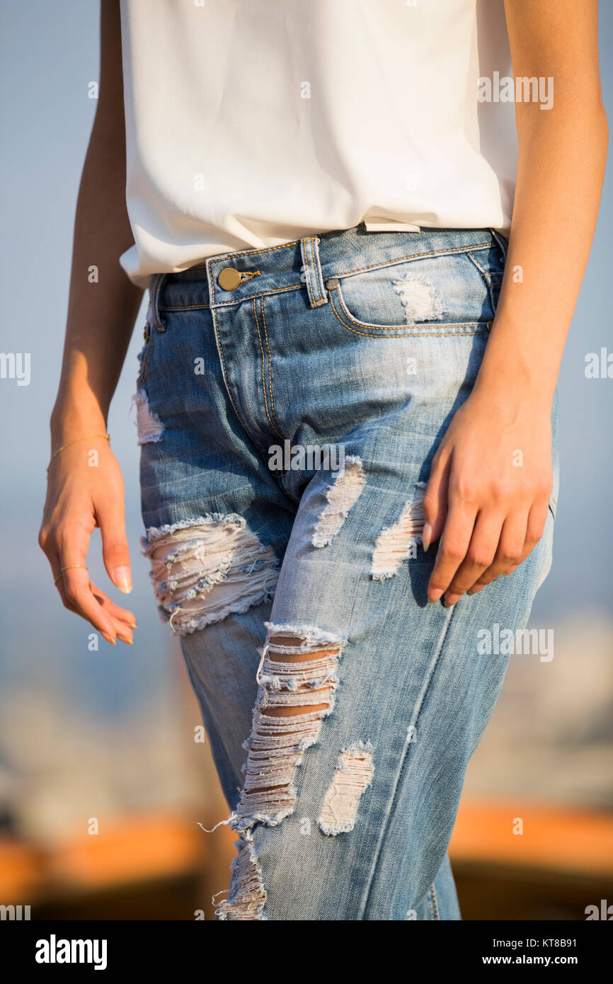 Cerca de una joven mujer vistiendo jeans rajados caminar al aire libre  Fotografía de stock - Alamy