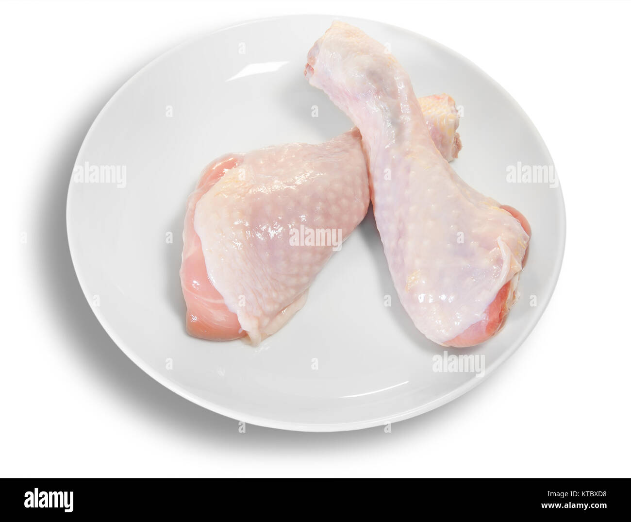 Dos piernas de pollo crudo en la placa blanca. Foto de stock